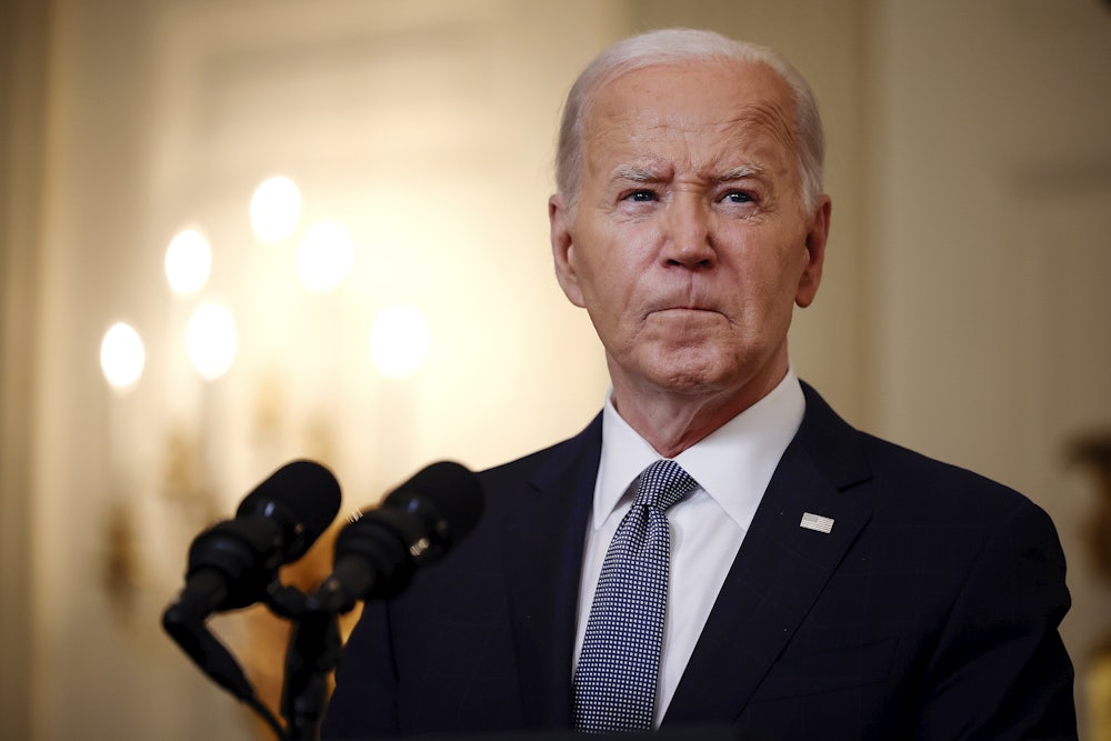 Joe Biden purses his lips while giving a speech behind a lectern.