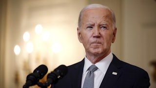 Joe Biden purses his lips while giving a speech behind a lectern.