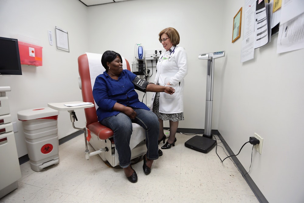 A doctor takes a patient's blood pressure in an examination room.