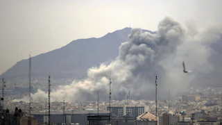 Smoke rises from the Tehran, Iran skyline with the Elborz mountains visible in the background.