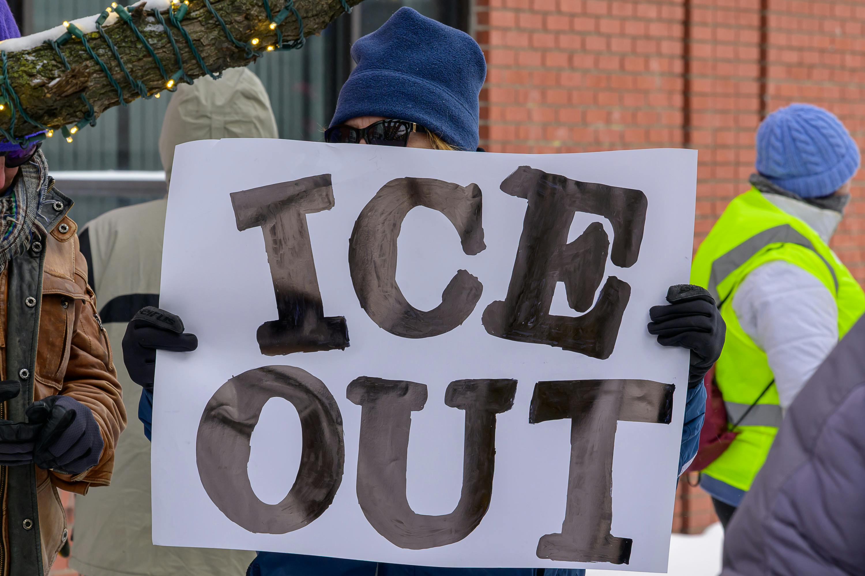 A person holds a sign that says, "ICE out" at a protest