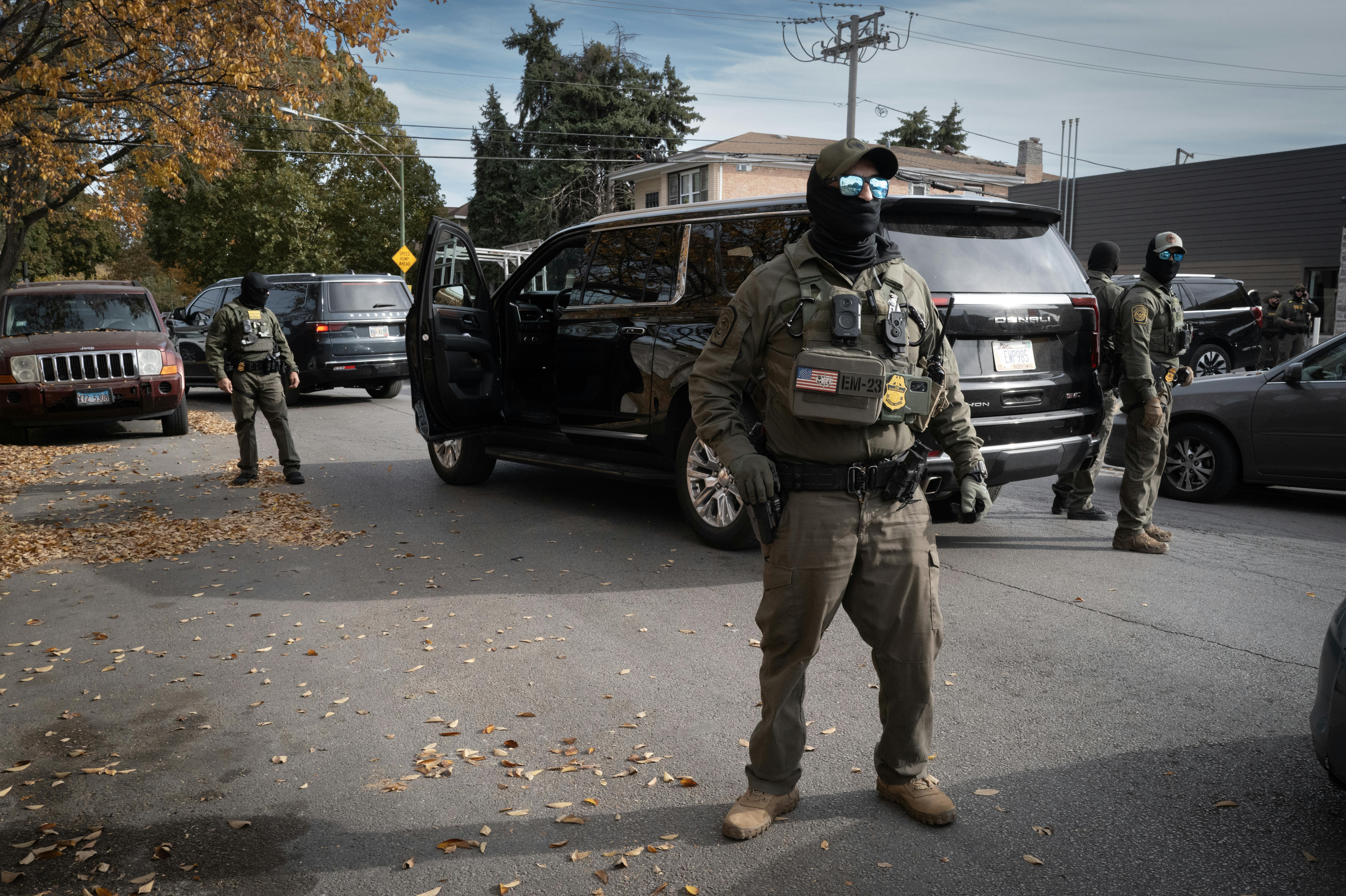 Masked federal agents stand in the street.