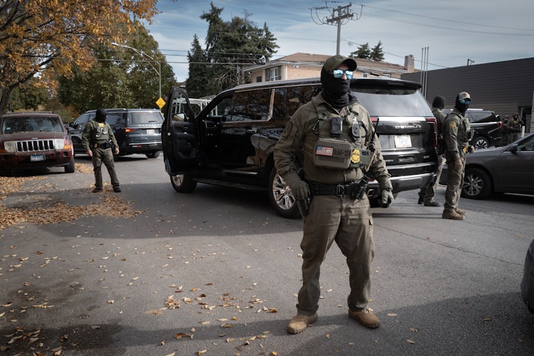 Masked federal agents stand in the street.