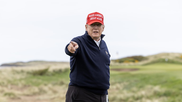 Donlad Trump wears a MAGA hat on a golf field