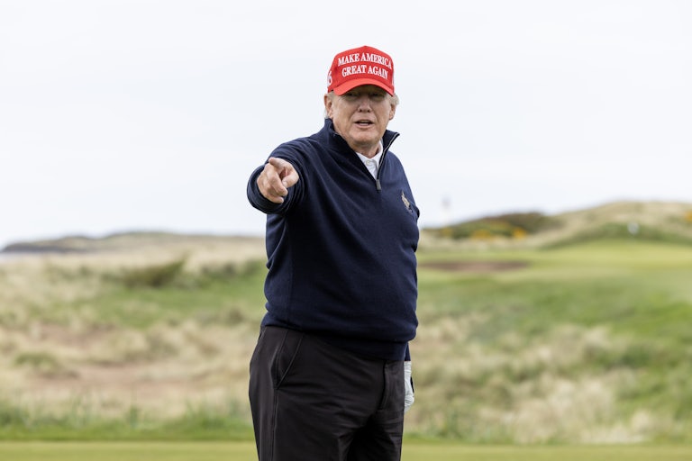 Donlad Trump wears a MAGA hat on a golf field