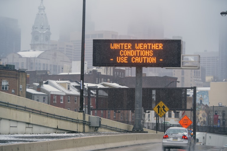 A sign on the road reads "Winter Weather Conditions—Use Caution."