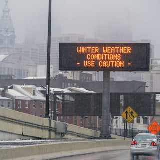 A sign on the road reads "Winter Weather Conditions—Use Caution."