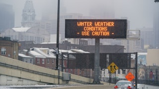 A sign on the road reads "Winter Weather Conditions Use Caution."