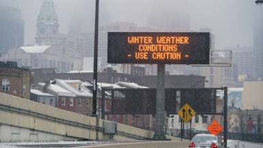 A sign on the road reads "Winter Weather Conditions Use Caution."