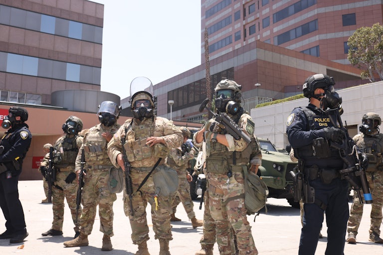 National Guard members and police officers on the streets of Los Angeles wear gas masks.