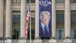 A large banner showing a picture of President Donald Trump on the U.S. Department of Agriculture. The sign reads "USDA Growing America Since 1862."