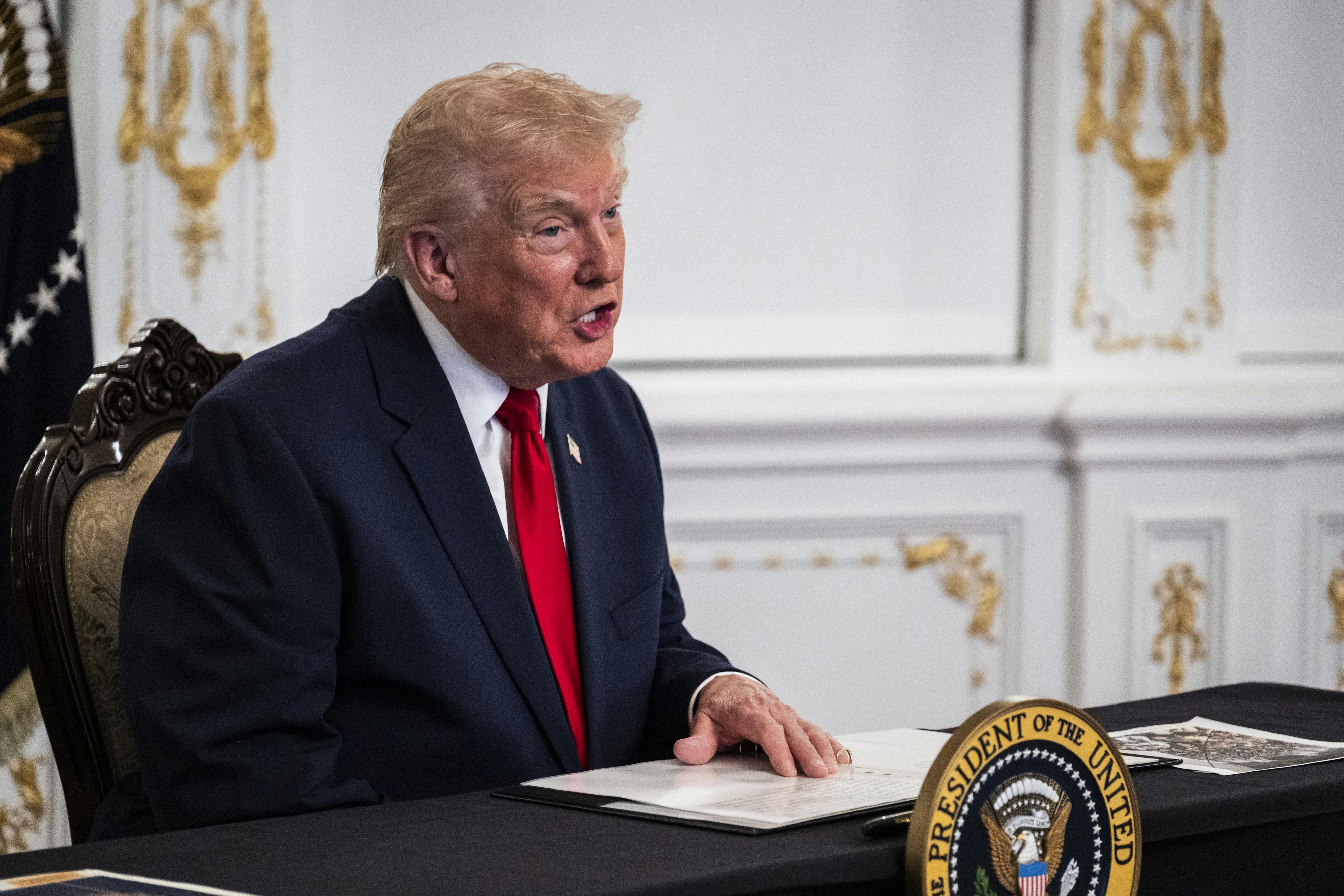 Donald Trump speaks while sitting at a desk in Mar-a-Lago
