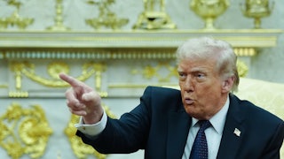 Donald Trump puckers his lips and points while sitting in the Oval Office