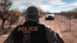 An ICE agent faces away from the camera