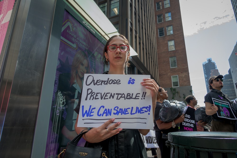 A woman holds a sign that reads "Overdose is preventable! We can save lives!" at a demonstration in New York City.