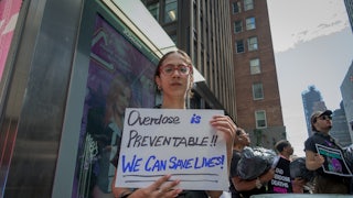A woman holds a sign that reads "Overdose is preventable! We can save lives!" at a demonstration in New York City.