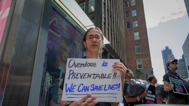 A woman holds a sign that reads "Overdose is preventable! We can save lives!" at a demonstration in New York City.