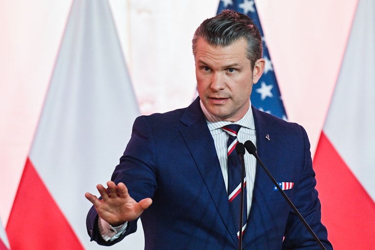 Pete Hegspeth speaks in front of the Polish and U.S. flags.
