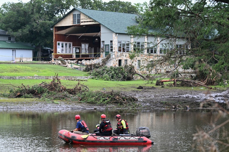 A search and rescue team rows in a bloat on the Guadalupe River near a damaged building in Texas following severe floods.