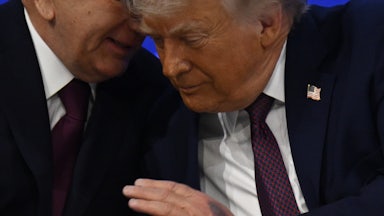 Donald Trump listens as Uzbek President Shavkat Mirziyoyev speaks in his ear. A large bruise is visible on the back of Trump's hand