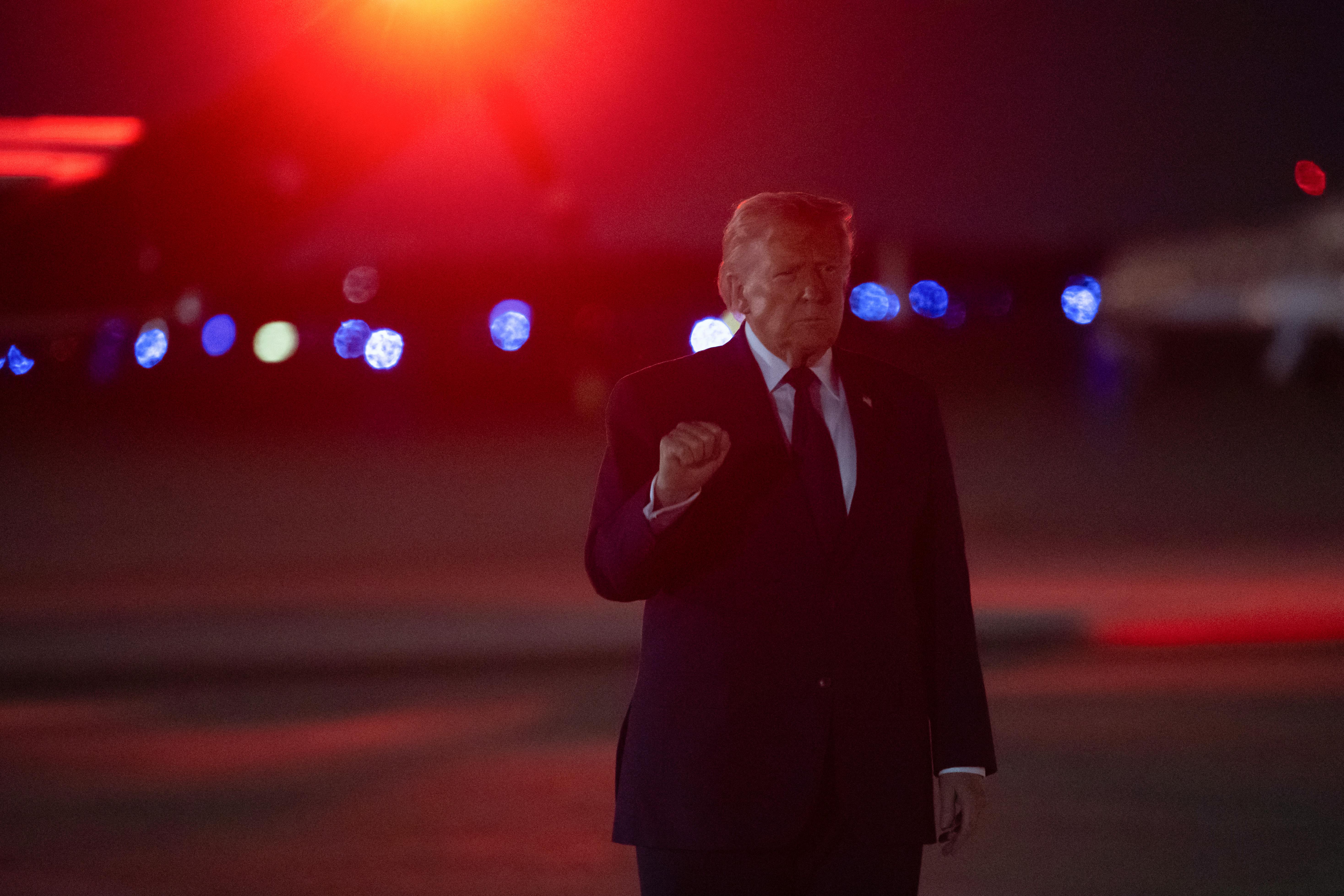 Donald Trump holds up a fist while walking at night 