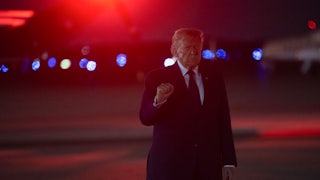 Donald Trump holds up a fist while walking at night