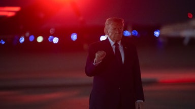 Donald Trump holds up a fist while walking at night