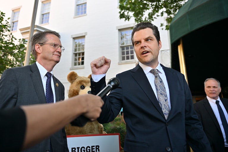 Matt Gaetz raises a fist as a microphone is extended toward him.