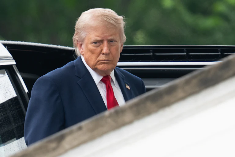 Donald Trump stands near a car