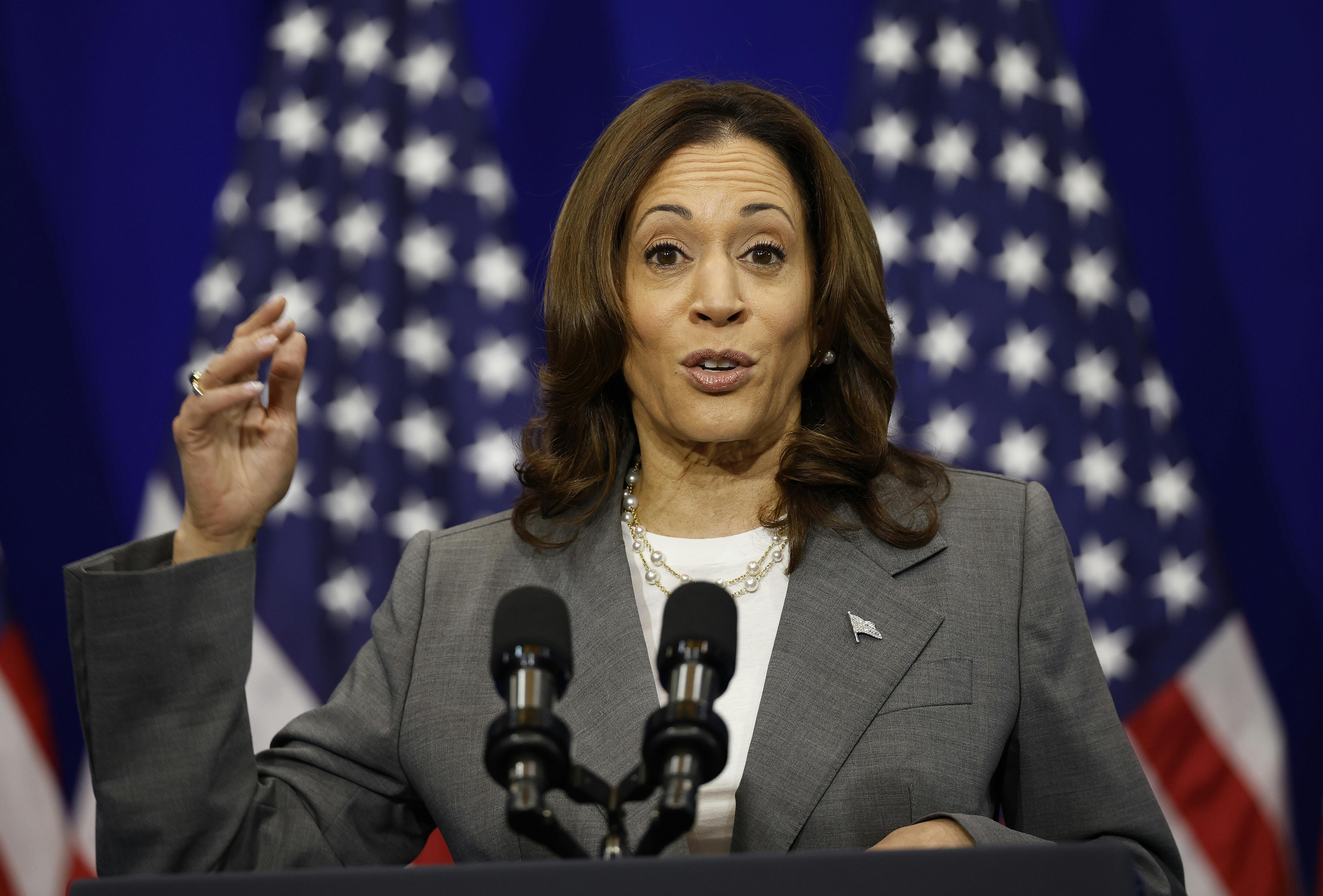 Kamala Harris speaks at a podium with American flags behind her.