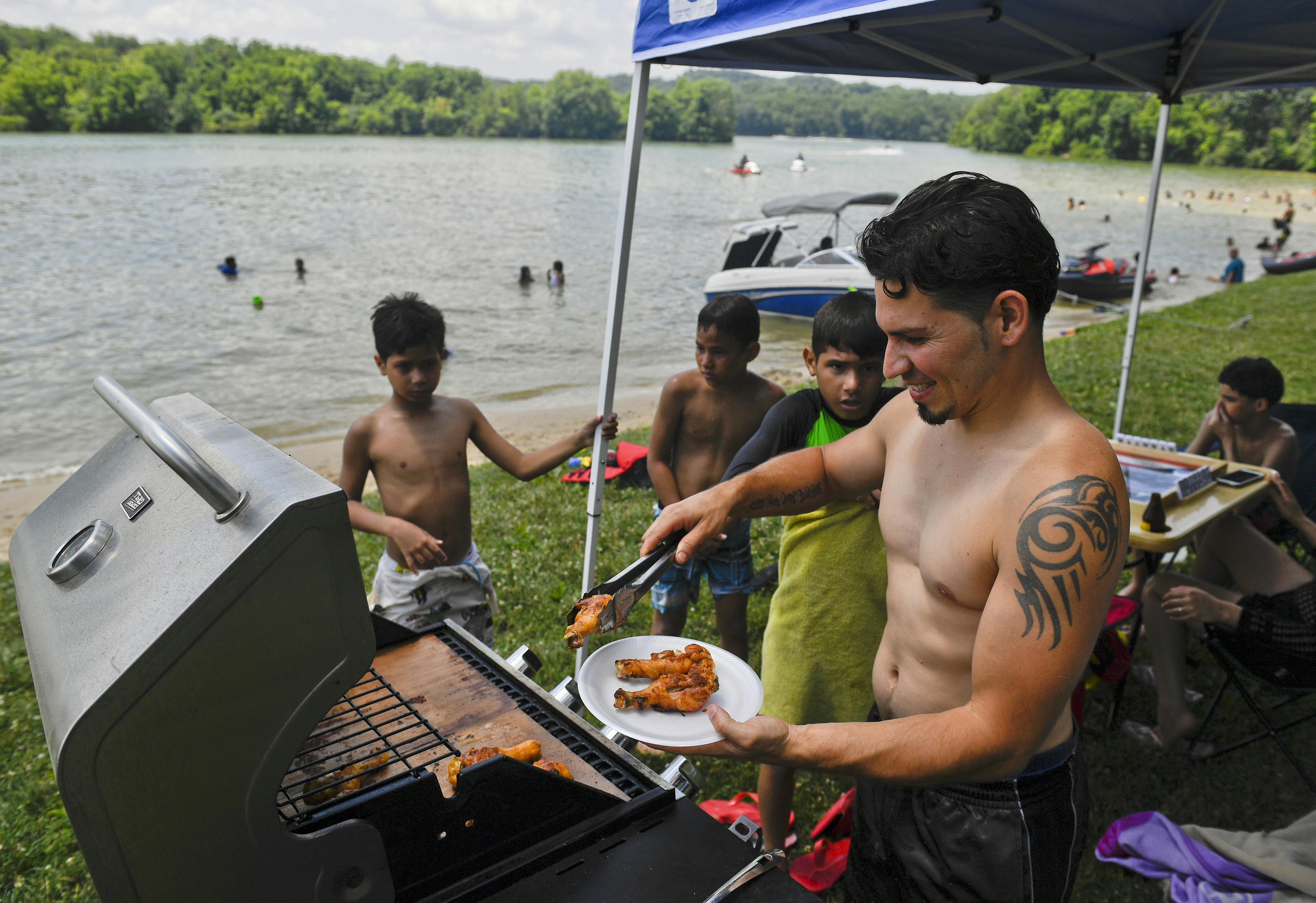 Rafael Burgos works the grill at his family's spot by Blue Marsh Lake in Pennsylvania on Fourth of July weekend in 2020. 