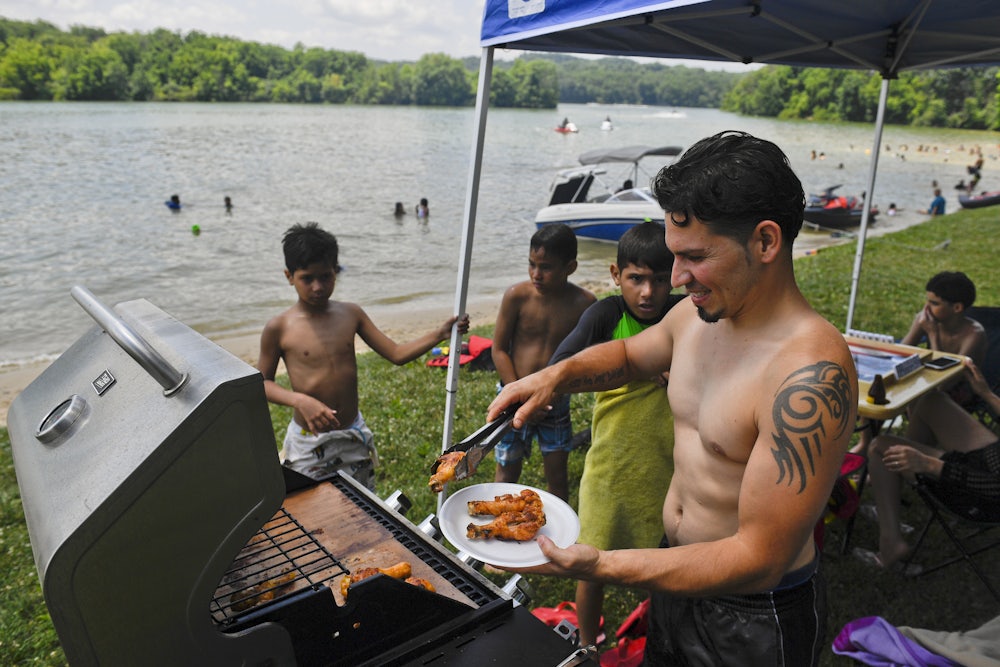 Rafael Burgos works the grill at his family's spot by Blue Marsh Lake in Pennsylvania on Fourth of July weekend in 2020.