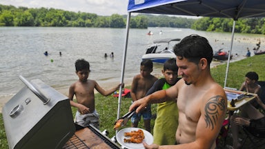 Rafael Burgos works the grill at his family's spot by Blue Marsh Lake in Pennsylvania on Fourth of July weekend in 2020.