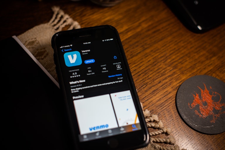 A phone on a table has the Venmo app open in the App store.