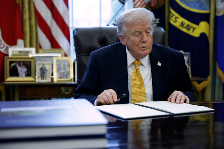 Donald Trump prepares to sign paperwork during a White House signing ceremony.