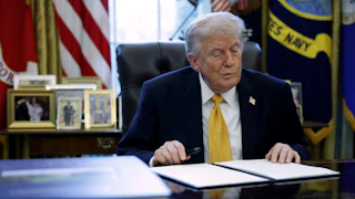 Donald Trump prepares to sign paperwork during a White House signing ceremony.
