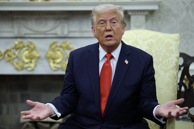 Donald Trump hols his hands out the side and speaks while sitting in the Oval Office
