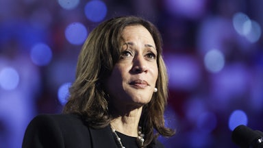 Kamala Harris looks up while standing in front of a microphone