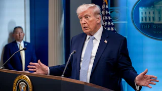 Donald Trump holds his hands out to the side while speaking at a podium during a press conference