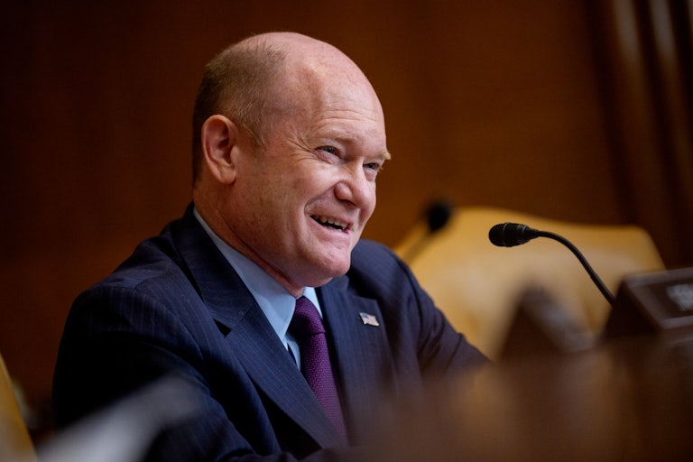 Democratic Senator Chris Coons laughs during a congressional hearing.