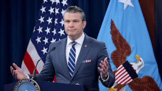 Defense Secretary Pete Hegseth shrugs while standing at a podium
