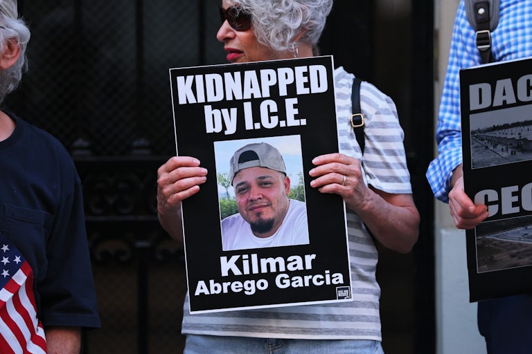 A woman wholds a sign reading "Kidnapped: Kilmar Abrego Garcia" with a picture of Garcia wearing a baseball hat