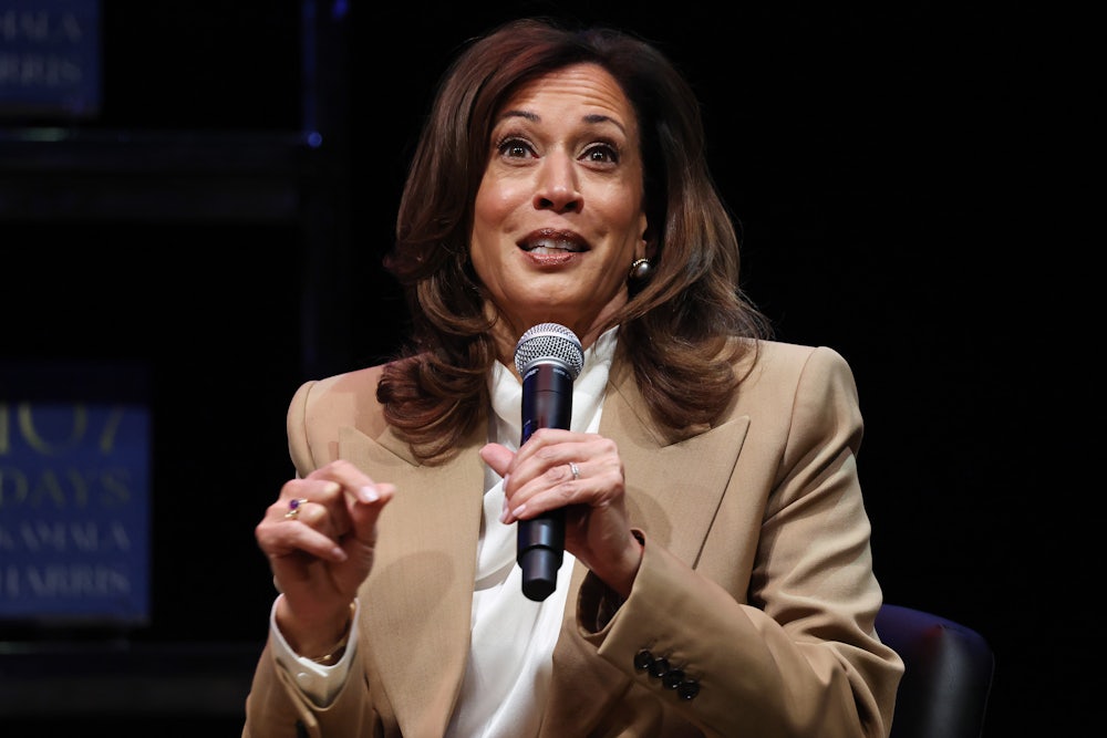 Kamala Harris holds a microphone and gestures while speaking.