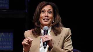 Kamala Harris holds a microphone and gestures while speaking.