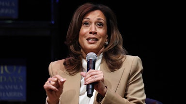 Kamala Harris holds a microphone and gestures while speaking.