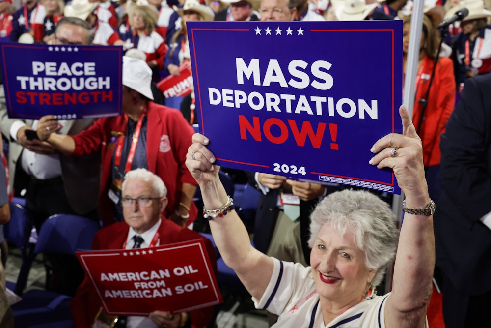 People hold signs that read "Mass Deportation Now!" on the third day of the Republican National Convention at the Fiserv Forum on July 17, 2024 in Milwaukee, Wisconsin.