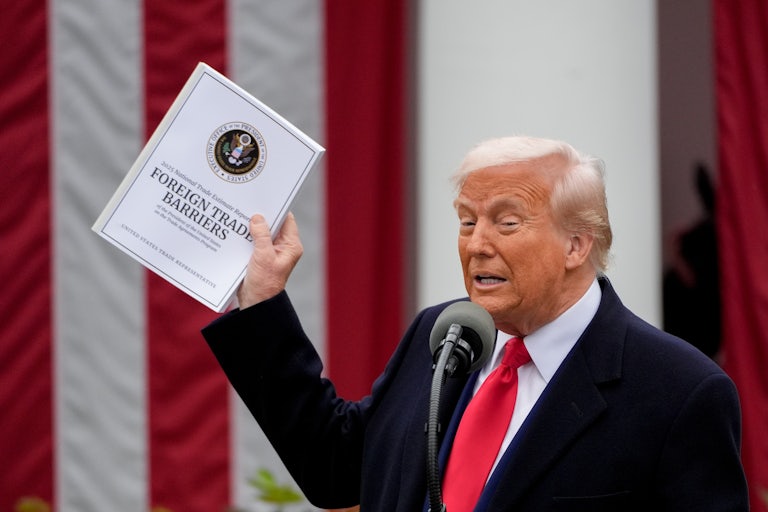 Donald Trump holds up a booklet on "foreign trade barriers" while speaking to reporters in the White House Rose Garden