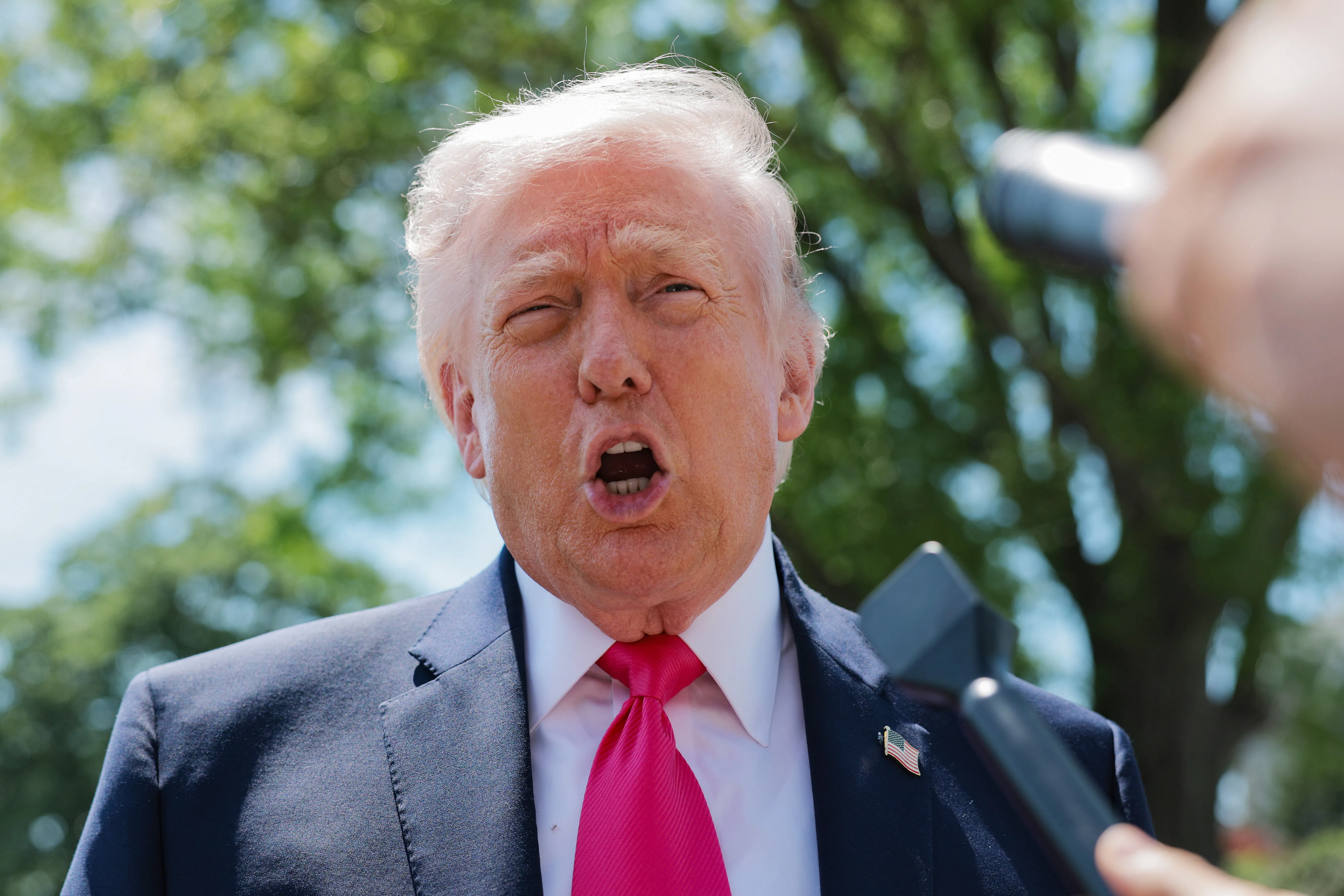 Donald Trump speaking into a mic.