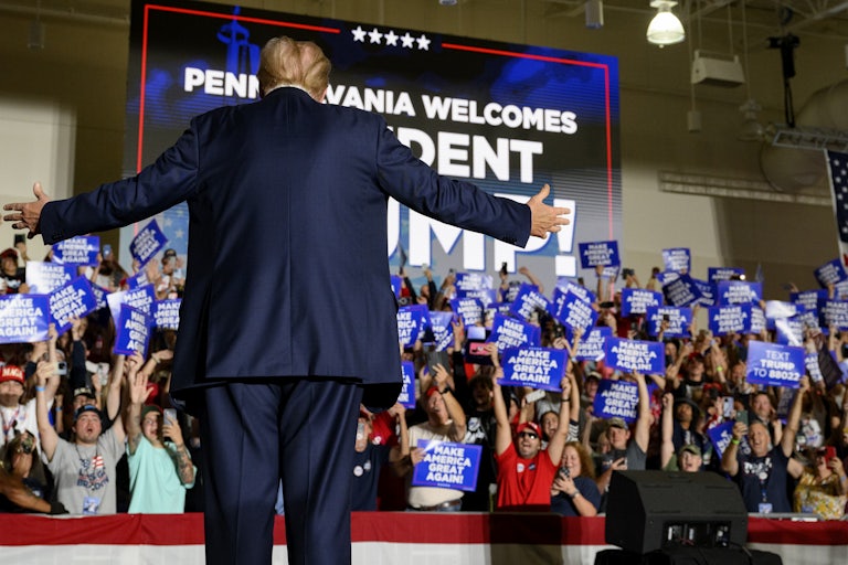 Donald Trump holds his arms out while facing the crowd at a campaign rally
