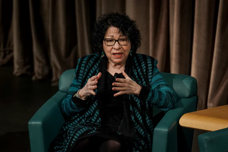 Supreme Court Justice Sonia Sotomayor gestures and speaks while sitting at an event